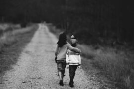 Black and white photo of two children walking away from the camera down an empty road. The taller child has an arm around the shorter one. Protection is an anti-child sex trafficking effort.