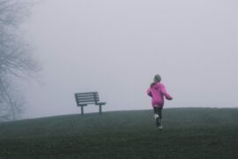 A young girl runnung away from the camera. She is running into the fog with a bench in the distance. Is she running away from sexual abuse?