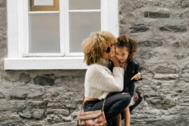 Open communication is a critical defense for the prevention of grooming. This mother and child are communicating with each other through speech outside near a stone building.