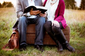 Focusing on the spiritual richness of love brings couples closer together and bonds them more deeply. This photo shows a couple sitting close together in a field, reading the Bible with each other.